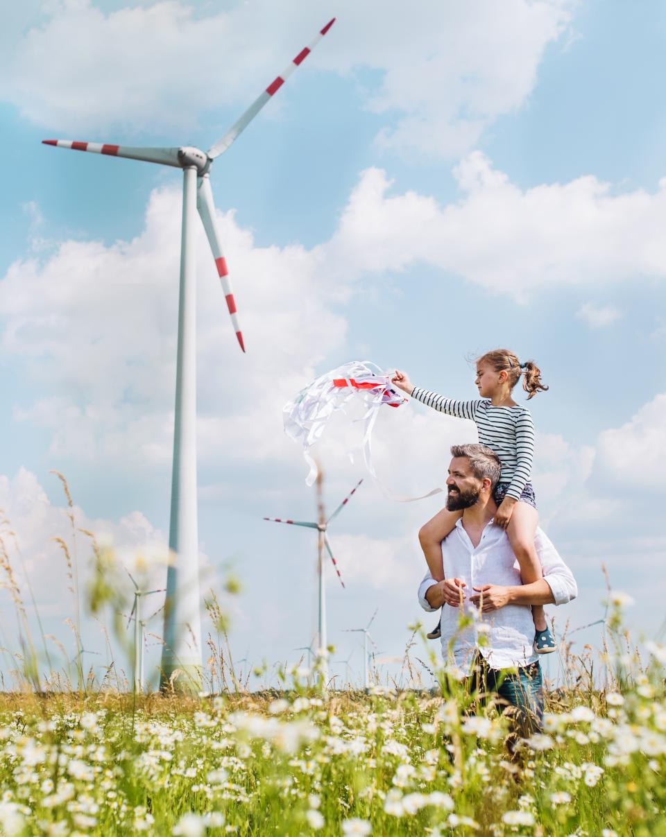 Vater mit Tochter beim Spaziergang zwischen Windrädern