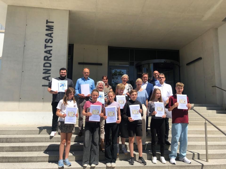Preisverleihung vor dem Landratsamt Schülerinnen und Schüler sowie Lehrende stehen mit ihren Auszeichnungen vor dem Landratsamt un.